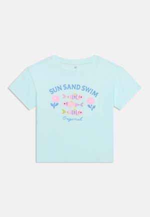 T-shirt bleu clair à manches courtes avec trois poissons colorés, des fleurs roses et le texte "SUN SAND SWIM Original" sur le devant.