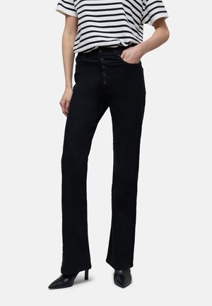 Schwarze, weit ausgestellte Hosen mit hoher Taille, featuring einen Fünf-Knopf-Verschluss vorne und einer glatten Textur, kombiniert mit einem gestreiften Hemd und High Heels.