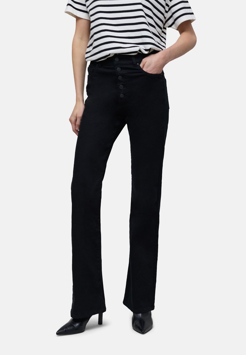 Pantalons évasés noirs à taille haute, dotés d'une fermeture frontale à cinq boutons et d'une texture lisse, associés à une chemise rayée et des talons.