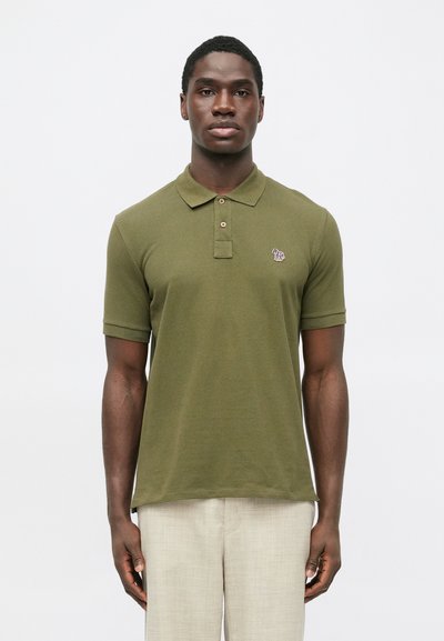 Polo vert olive à manches courtes, patte de boutonnage à deux boutons et petit logo brodé. Texture douce et détail de col côtelé.