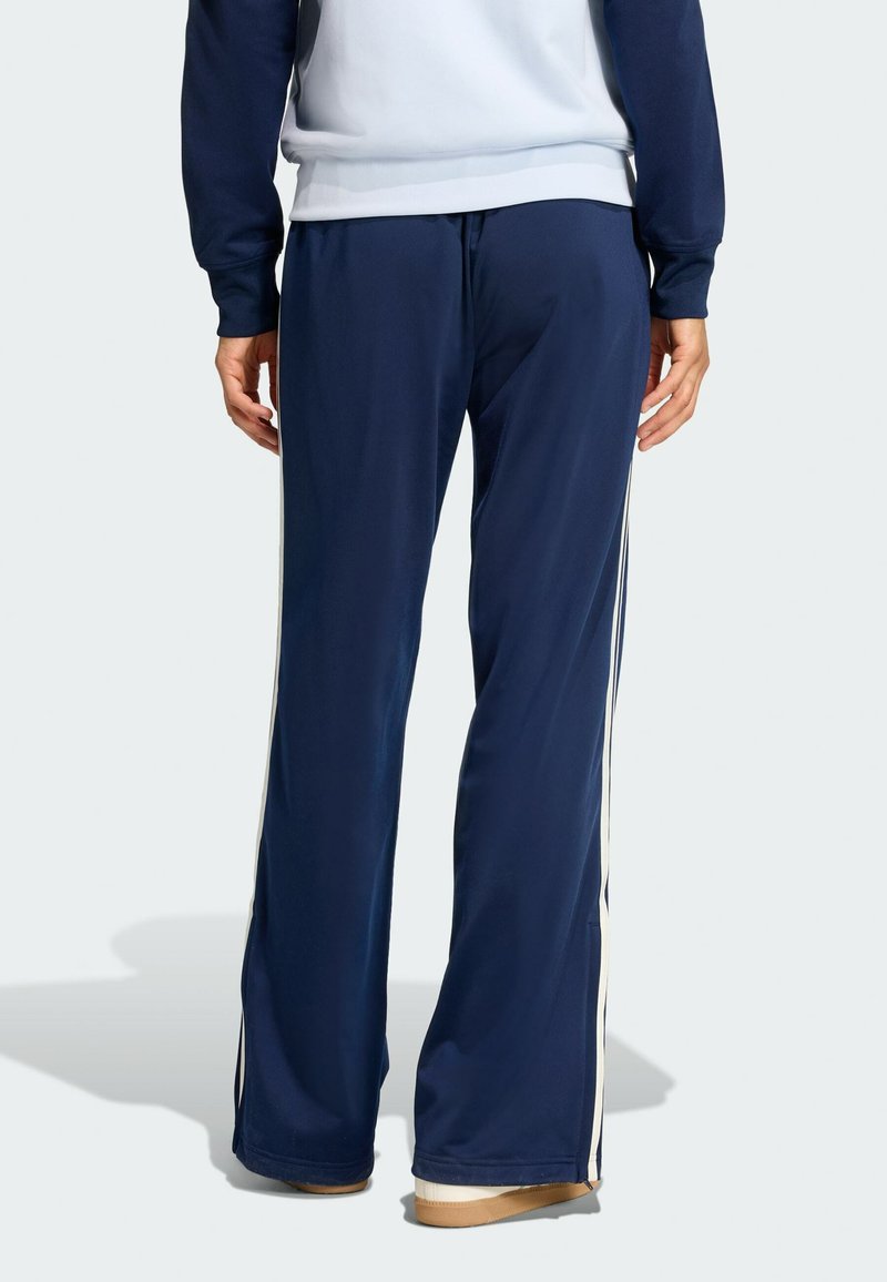 Pantalon de sport bleu marine avec une coupe droite, des bandes blanches verticales sur les côtés et une taille élastique pour le confort.