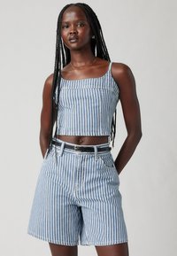 Top cropped de denim azul riscado com alças finas, combinado com uns calções de cintura alta correspondentes. Design com cinto e com bolsos frontais e laterais.