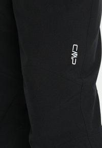 Zwarte outdoorbroek, gemaakt van flexibel materiaal, met een gestikt ontwerp en een wit CMP-logo aan de zijkant. Slim fit met taps toelopende pijpen.