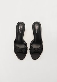Zwarte hoge hakken sandalen met een satijnen afwerking, met een open teen, een geknoopt voorpaneel en een slank ontwerp.
