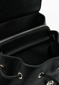 Black leather bucket bag with a silver zippered compartment, textured exterior, and black interior, featuring drawstring closure and metal accents.