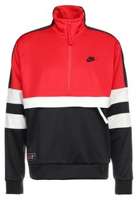 Röd och svart zip-up sweatshirt med vita randdetaljer, som har hög krage, Nike-logotyp och en märkning med "AIR" vid nederkanten.