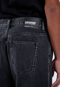 Černé džíny z denimu s vybledlým vzhledem, s cedulkou na zadním pasu, dvěma zadními kapsami a kontrastním šitím.