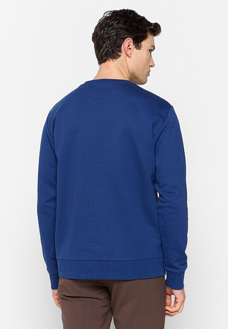 Sudadera azul con mangas largas, cuello redondo y puños y dobladillo acanalados. La tela parece suave y ligeramente texturizada.