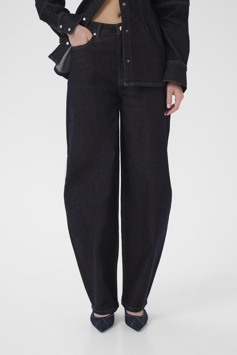 Dark blue denim wide-leg pants with a high waist, featuring side pockets and contrast stitching, paired with pointed-toe navy shoes.
