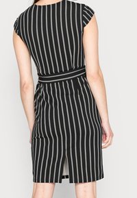 Černobílé pruhované šaty s krátkými rukávy, vypasovaným pasem a zadním rozparkem. Vyrobené z měkké látky s elegantní siluetou.