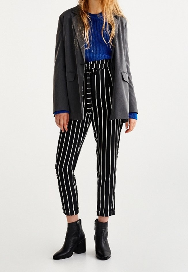 Blazer gris, pull bleu côtelé, pantalon taille haute rayé noir et blanc, et bottines noires à talons. Design simple et structuré.