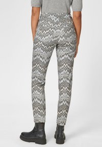Gemusterte Hosen mit einem Zickzackdesign in Grau, Weiß und sanften Blautönen. Das Material wirkt strukturiert, hat eine schmale Passform und Taschen.