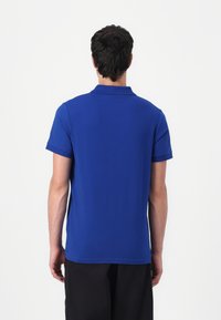 Koningsblauwe polo met een klassieke kraag, korte mouwen en een gladde textuur. Eenvoudig ontwerp, geen zichtbare patronen of accenten.