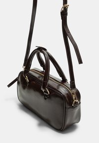 Sac à main rectangulaire en cuir marron foncé avec deux poignées courtes, une fermeture éclair dorée et une longue sangle ajustable.