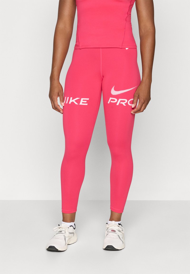 Rosa Nike Pro leggings med en glatt tekstur, med store hvite "NIKE" og "PRO" logoer på sidene, kombinert med hvite idrettssko.