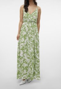 Zelené květinové maxi šaty s bílými vzory, výstřihem do V a nastavitelnými ramínky. Plynulá tkanina, zúžený pas a design sahající až po kotníky.