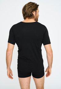 Zwarte short-sleeve shirt van zacht materiaal, met een ronde halslijn en een casual pasvorm, gecombineerd met zwarte shorts.