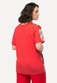 Rød bomulds t-shirt med korte ærmer, med et blomster-mønstret sidepanel og en afslappet pasform. Glat tekstur og rund halsdesign.
