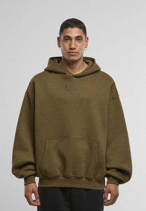 Alyvuogių žalios spalvos džemperis su gobtuvu, pagamintas iš minkštos medžiagos, su priekine kišene, ribotomis rankogaliais ir siuvinėtu tekstu krūtinės srityje, laisvo silueto.