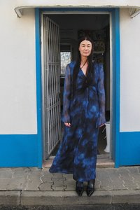Robe longue et fluide avec un motif tie-dye bleu et noir. Tissu transparent avec des manches longues et une conception portefeuille. Portée avec des chaussures noires pointues.