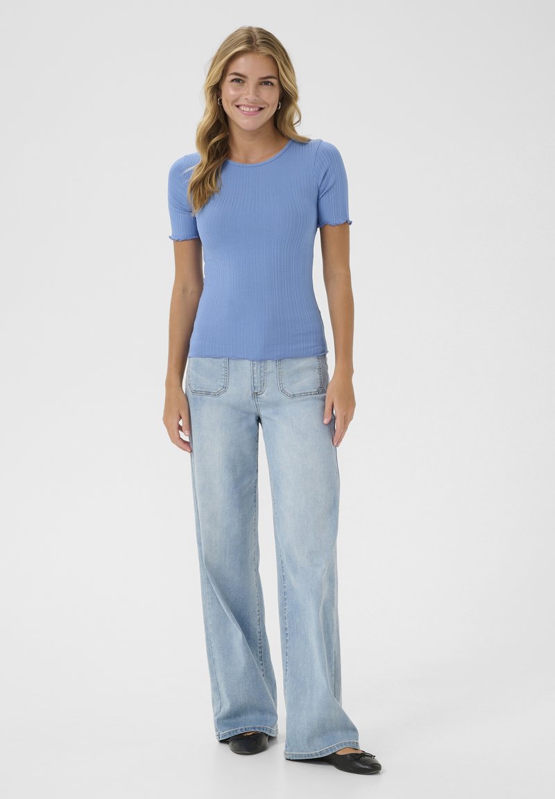 Light blue ribbed short-sleeve top paired with light wash wide-leg jeans. The outfit features a relaxed fit and subtle ruffle accents on the sleeves.