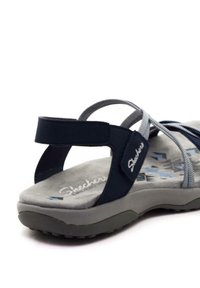 Infradito blu navy con cinturini in tessuto e soletta grigia imbottita. Presenta una suola testurizzata e il logo del marchio sul lato. Regolabile per la vestibilità.