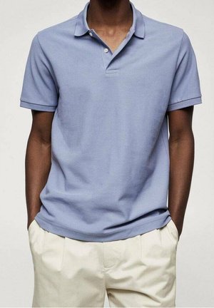 Polo de color azul claro hecho de algodón, con cuello y tapeta de dos botones, combinado con pantalones beige. Tela suave y corte relajado.