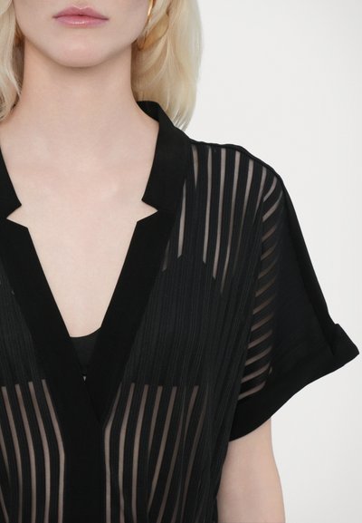 Blusa negra transparente con rayas verticales, mangas cortas y cuello con muesca, superpuesta sobre una camiseta negra sólida debajo.