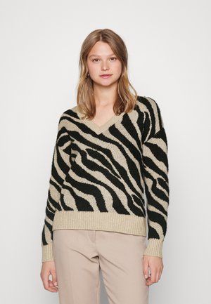 V-hals striktrøje med sorte og beige zebrastriber, lavet af blødt strikkemateriale; har ribbede manchetter og en ribkant forneden for ekstra tekstur.