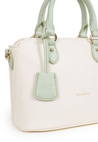 Borsa bianca con texture e dettagli in verde menta, dotata di manici doppi, accessori in metallo dorato e un piccolo cartellino con iniziali in rilievo.