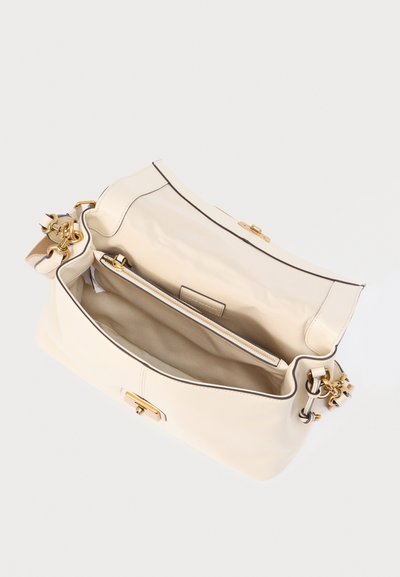 Kremfarvet læder skuldertaske med gulddetaljer, åben klap der viser inderlomme med lynlås og stofforing.