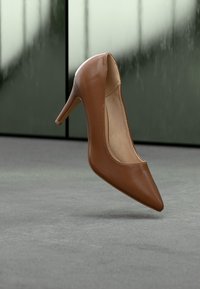 Καφέ δερμάτινο ψηλοτάκουνο παπούτσι με μυτερή μύτη και ομαλή υφή, με λεπτό τακούνι στιλέτο και μινιμαλιστικό σχεδιασμό.