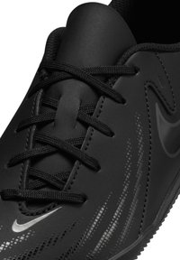 Schwarze Sportschuhe mit einem glatten, synthetischen Obermaterial, ausgestattet mit schwarzen Schnürsenkeln und dezenten strukturierten Akzenten. Nike-Logo an der Seite sichtbar.
