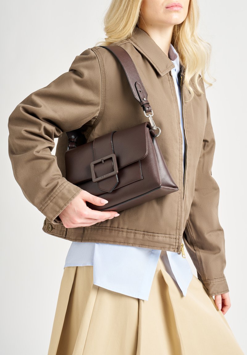 Borsa a tracolla in pelle marrone con forma rettangolare, chiusura a pattina e dettaglio fibbia quadrata. Presenta una tracolla e una finitura testurizzata.