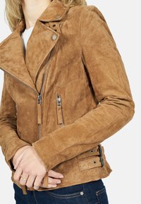 Veste de moto en daim marron avec un col cranté, fermeture éclair à l'avant, deux poches latérales et des accents de boucle réglables sur les côtés.