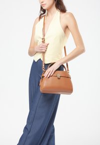 Borsa in pelle color tan con forma strutturata, manico superiore e tracolla removibile. Presenta una chiusura a gancio e una superficie liscia.