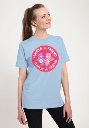 Lyseblå bomulds-t-shirt med et rundt grafisk motiv, der viser to tegneserie-bjørne og teksten "Alltid en Ven" i pink og hvid.