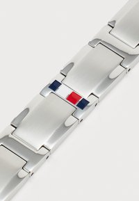 Stålarmbånd til klokke med en glatt finish, med et sentralt design av røde, hvite og blå rektangulære detaljer.