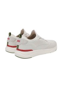 Sneaker bianche in rete con forma arrotondata, accenti rossi e verdi, superficie texturizzata e dettagli del logo sulla linguetta del tallone.