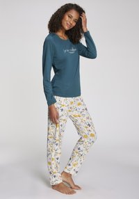 Turquoise långärmad tröja med vit skrift och pyjamabyxor med blommönster i gula, blå och gröna nyanser. Mjuk, lättviktig tyg.