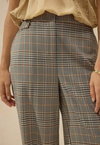 Karierte Hose mit tailliertem Schnitt; Baumwollstoff in Schwarz-, Weiß- und Brauntönen; mit Seitentaschen und subtiler Textur.