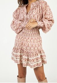 Robe à manches longues et col, présentant un motif abstrait rose et crème, une taille smockée, un ourlet à volants superposés et des détails en dentelle.