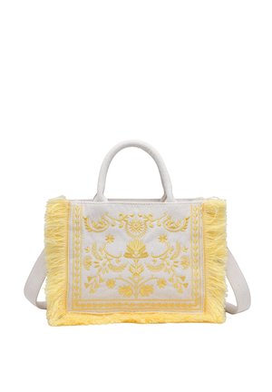 Sac à main en tissu beige avec broderie florale jaune, bords à franges jaunes, poignées supérieures et bandoulière réglable.