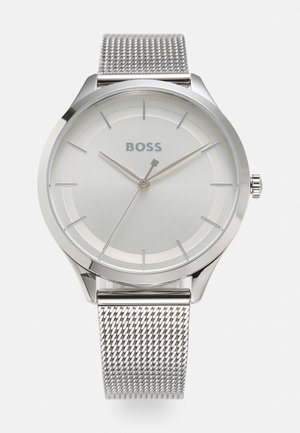 Montre-bracelet BOSS argentée avec cadran minimaliste, fines aiguilles des heures, trois aiguilles et bracelet en maille métallique.