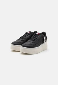 Svarta lädersneakers med perforerade detaljer, rund tå och tjock vit sula. Har en liten silverberlock på sidan.