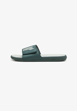 Dunkelgrüne Puma Slide-Sandale mit verstellbarem Riemen und weißem Puma-Logo oben, weißem strukturiertem Fußbett und flacher Sohle.