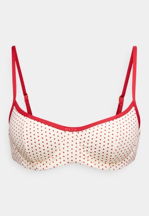 Soutien-gorge rouge à pois avec fond crème, bretelles rouges réglables et texture lisse. Présente un design structuré doublé avec armatures.