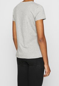 Camiseta gris de manga corta con un diseño clásico de cuello redondo, hecha de suave tela de algodón, con una textura lisa y un ajuste regular.