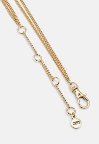 Gold metal chain, featuring a clip clasp, circular links, and a DKNY tag. The design is sleek with a smooth, polished finish.
