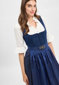 Blue traditional dress with a fitted bodice, ruffled white blouse sleeves, and decorative silver clasp at the waist, featuring a pleated skirt.